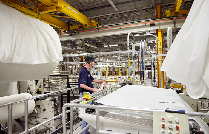 A man standing next to tissue being rolled out